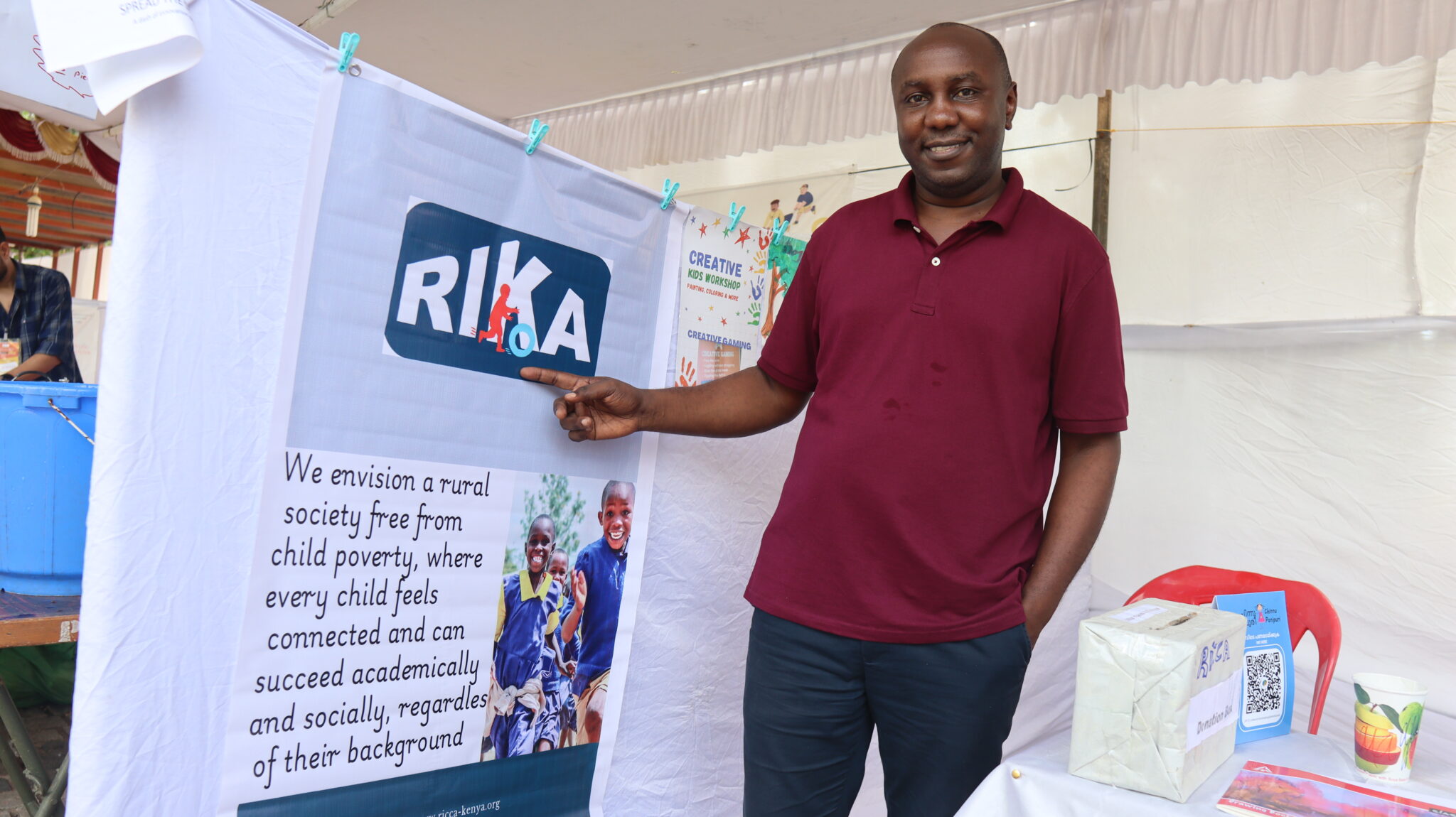 RICCA Founder, Kenneth explaining what we do through a banner, with our brand name, logo colours and approach